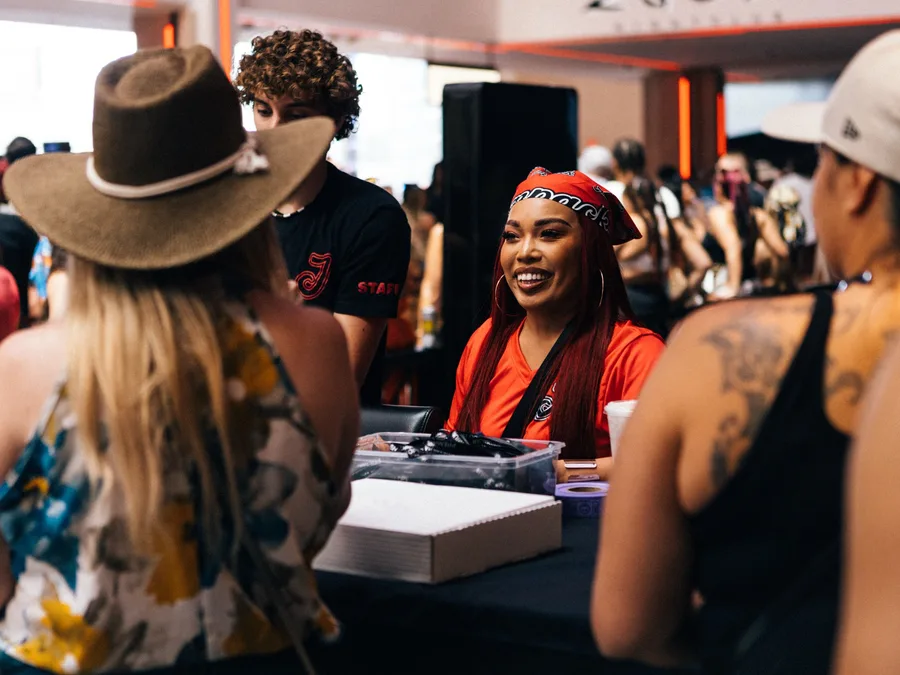 A Jampack staff member in a branded bandana smiling with guests across an event table