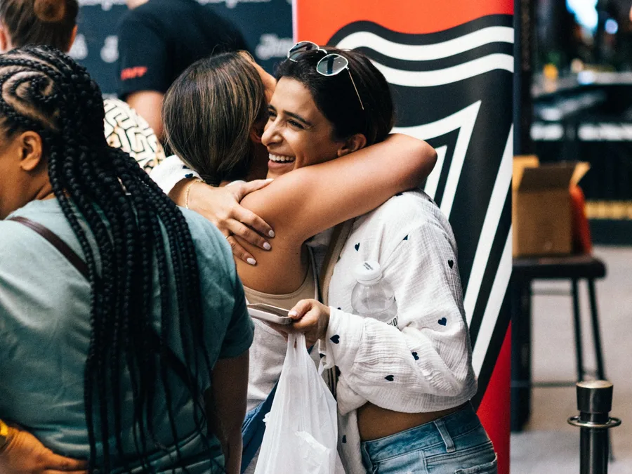 Two guests hugging in front of a Jampack banner at an event welcome