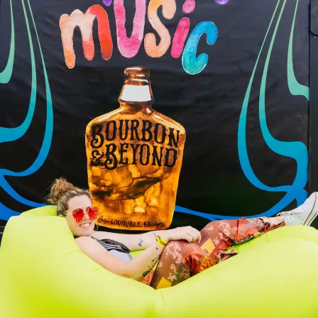 A guest on an inflatable in front of a painted Bourbon & Beyond mural